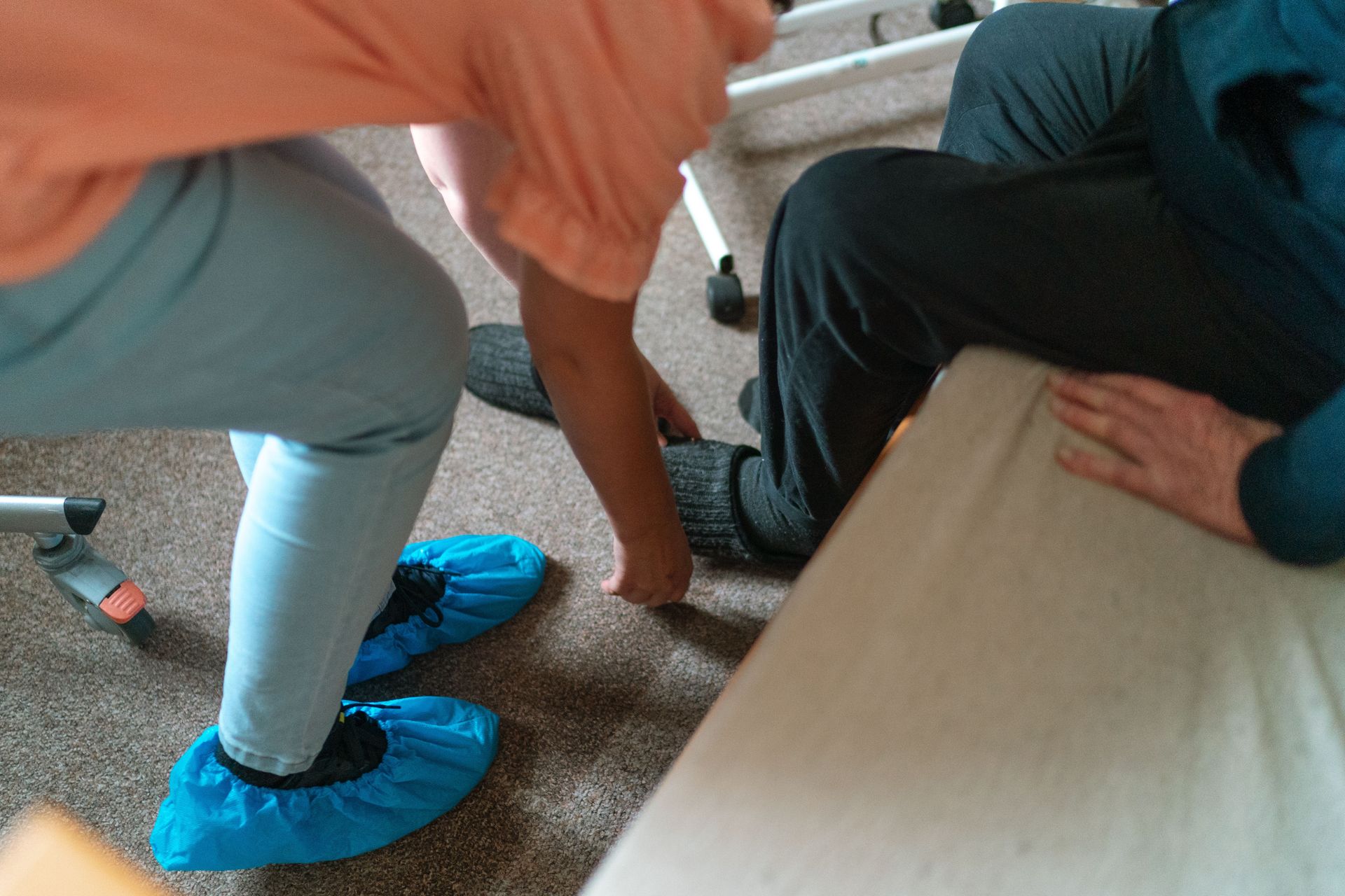 A caregiver helps a senior adult with socks in a cozy indoor setting in Praha.
